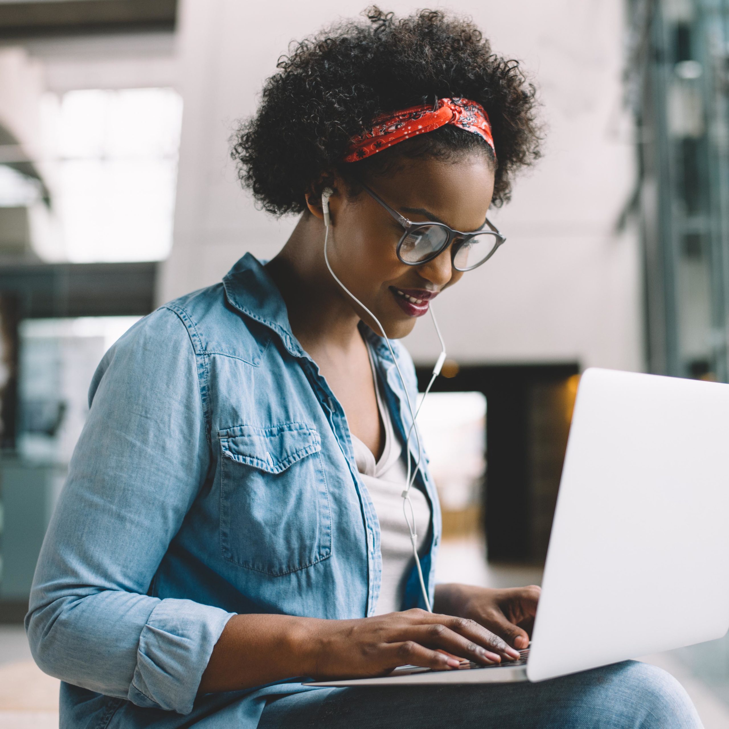 Smiling young African female university student sitting on a campus bench working on a laptop while preparing for an exam